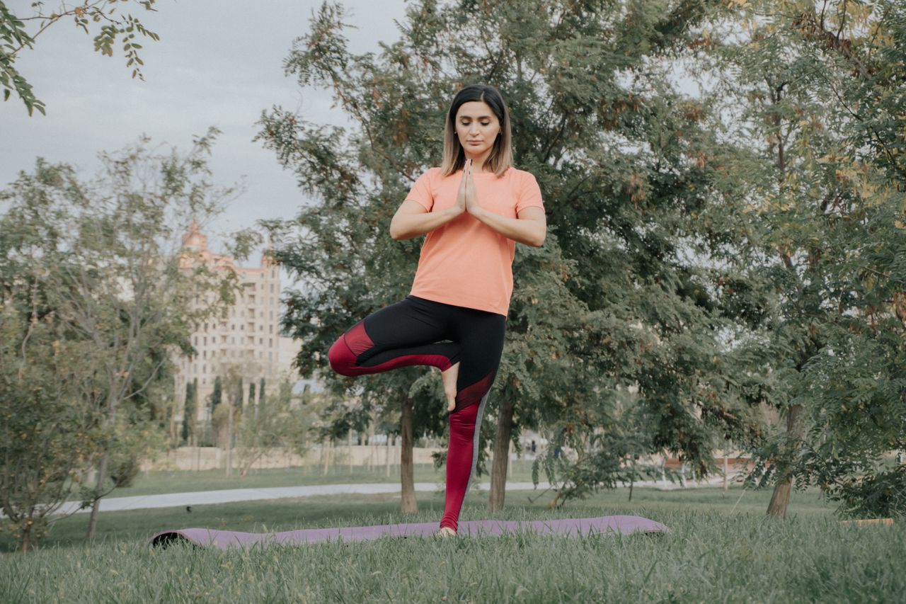 The Art of Drawing Readers In: Your attractive post title goes here A woman in yoga pose outdoors on a mat in a park, showcasing balance and mindfulness.